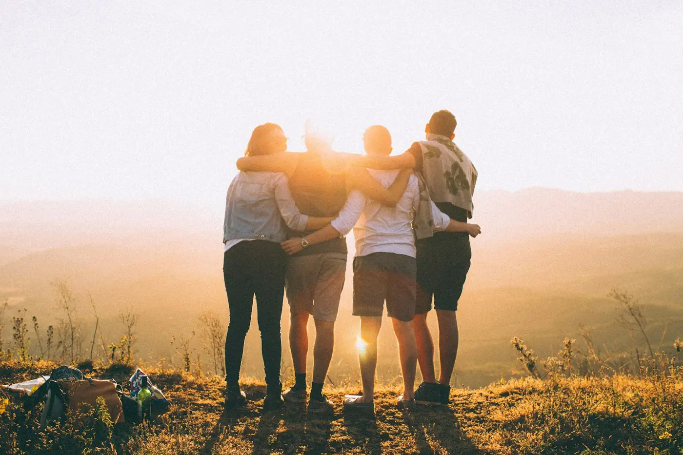 Grupo de amigos abrazados mirando el atardecer en una montaña